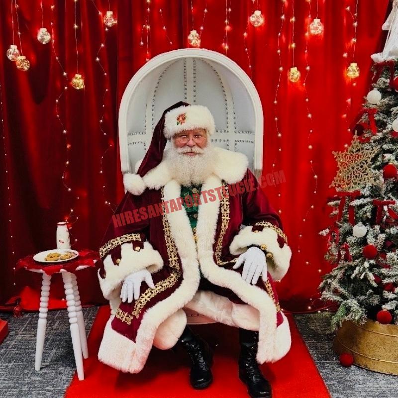 Santa for hire in Stuart, FL seated in a white chair with cookies and milk on the side table.