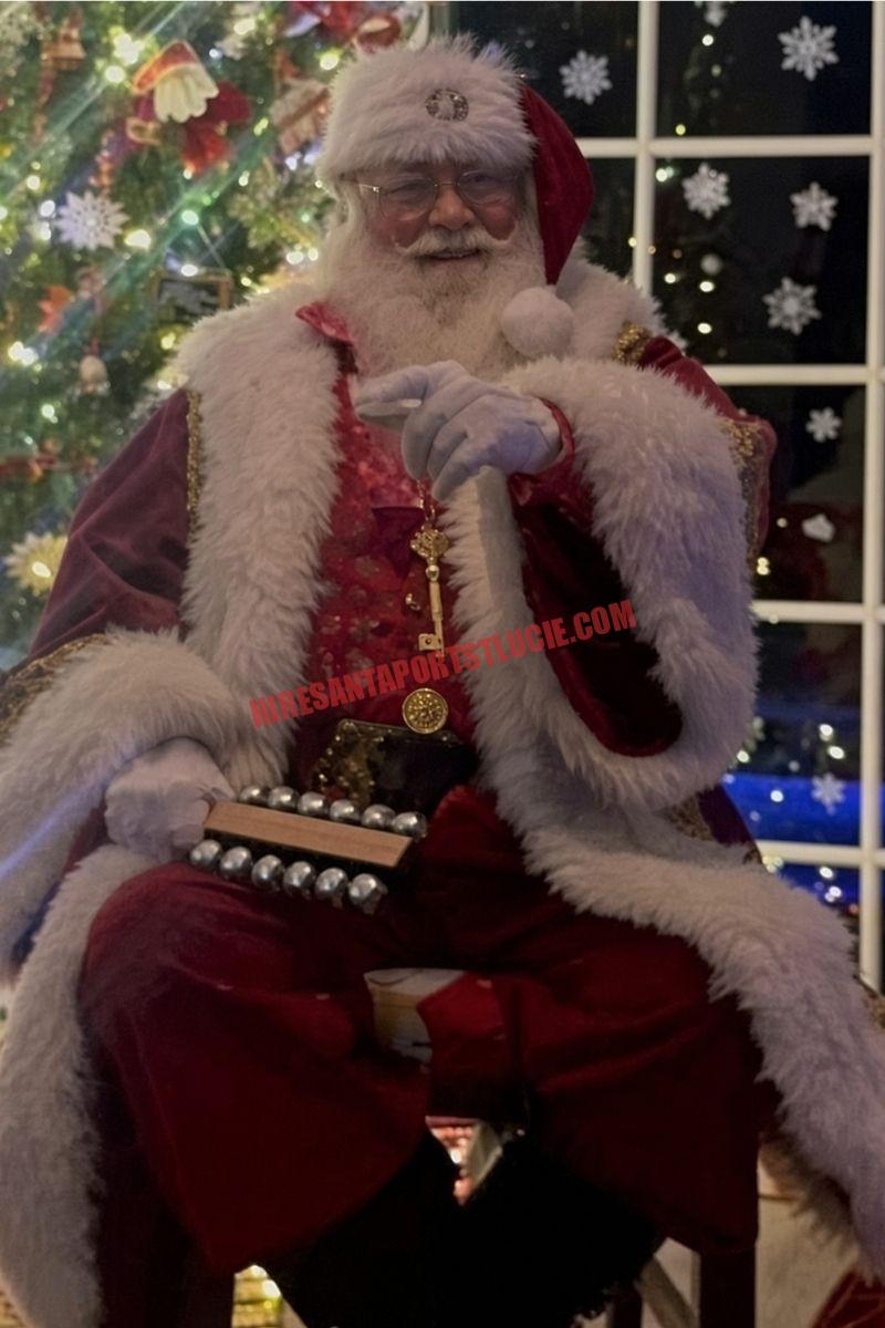 Santa home visit in Port St. Lucie: Santa seated with sleigh bells and a gold key beside a night window.